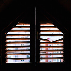 A view of the sunset from the attic through a loft window for ventilation, a beautiful red sunset in backlight