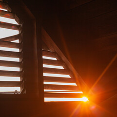 A view of the sunset from the attic through a loft window for ventilation, a beautiful red sunset in backlight