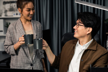 Sales managers discussing while drinking coffee cup together at over late night at home office, concept of modern working place with business report at breaking time with coworker at desk. Infobahn.