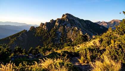 Mountain ridge under a blue sky during daylight, with a grassy foreground