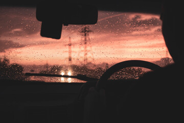 view from a car on the highway in bad weather conditions, rain and fog, at a beautiful red sunset