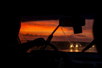 view from a car on the highway in bad weather conditions, rain and fog, at a beautiful red sunset