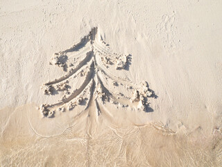 a Christmas tree painted on the sand of the beach and sea waves