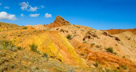 Colorful Fairytale rainbow canyon panorama landscape in Kyrgyzstan. Orange and yellow mountain valley Skazka canyon, rainbow mountain landscape all over the world in Pamir near Issyk Kul lake