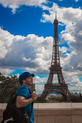 Turista disfrutando de la Torre Eiffel en Par&iacute;s, con boina azul parisina y sonrisa alegre.