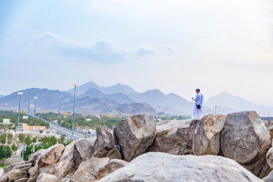 "Man in traditional attire standing on the rocks of Mount Arafat in Makkah, Saudi Arabia"