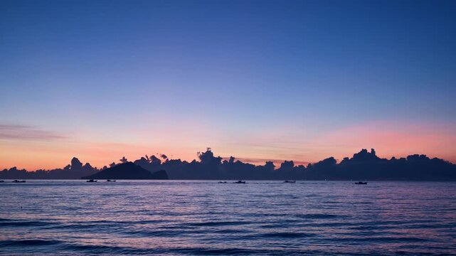 Fishing boats crosses the ocean at predawn near Guishan Island off the Zhuangwei coastline in Yilan Taiwan The sky displays beautiful orange pink and blue hues