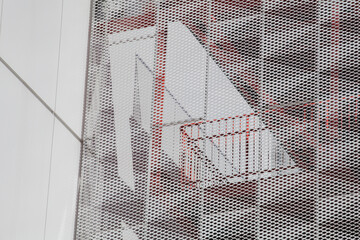 Perforated metal screen with red staircase behind facade in San Francisco building
