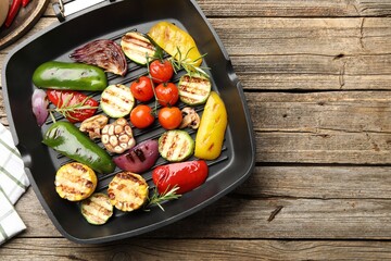 Pan with grilled vegetables and spices on wooden table, top view. Space for text