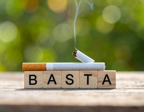 A broken cigarette rests on wooden blocks spelling "Basta