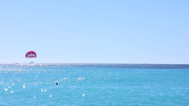 Beautiful view of wavy sea and people parasailing on sunny day