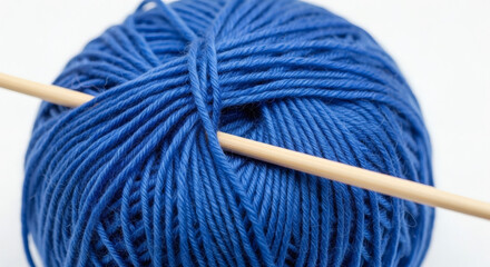 Close up shot of a ball of blue yarn with a wooden knitting needle
