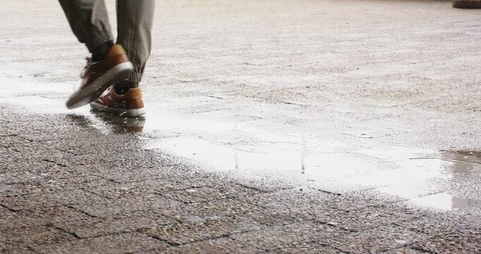 Spotting puddle under walkway, diverse senior men stepping to cross water, causing ripples