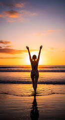 Woman’s back in patterned bikini, arms raised as she walks toward ocean, sun setting behind her
