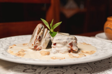 Round steak with white sauce and vegetables on a plate in a restaurant.