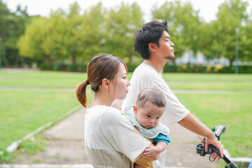 Fototapeta premium A man and a woman are walking with a baby in a stroller. The baby is wearing a blue shirt