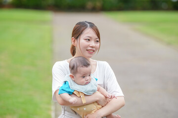 Fototapeta premium A woman is holding a baby in her arms. The baby is wearing a blue shirt. The woman is smiling