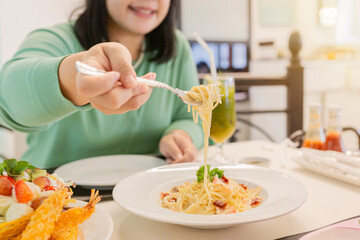 Female use fork to eat spaghetti carbonara, Creamy pasta carbonara with bacon bits and fresh parsley garnish served in white bowl. Classic Italian cuisine dish with rich sauce and herbs for dinner.