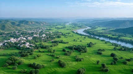 Obraz premium Aerial View of Lush Green Landscape with River and Rolling Hills Under Clear Blue Sky in Daytime