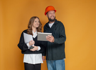 An architect and an engineer look into the distance with inspiration. A businesswoman and an engineer contractor look away with a positive emotion on an orange background for advertising construction 