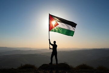 A silhouette of a person proudly holding the palestine flag on a mountain summit against a beautiful sunrise, symbolizing hope and freedom