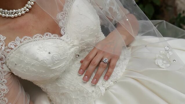 Overhead View of Bridal Engagement Ring and Wedding Bands Positioned on Lace Veil and Gown
