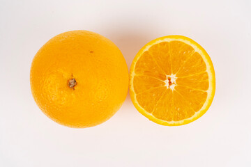 Whole orange and its cut half are placed side by side on a white background flat lay.