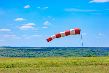 Red and white windsock on a sunny day in green pasture