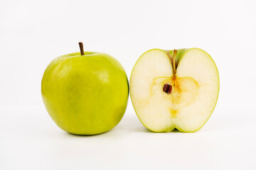 Whole green apple stands next to a freshly sliced half revealing crisp white flesh and core.
