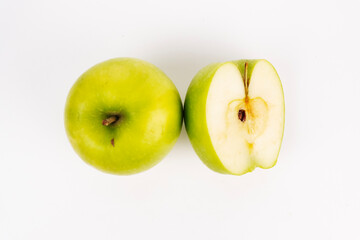 Overhead view captures whole green apple beside its sliced half on a clean white background.