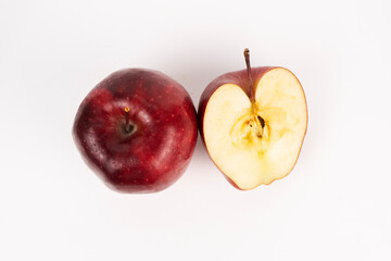 Whole red apple rests next to its sliced half revealing star pattern on a white surface from above.