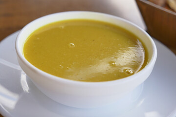 Delicious yellow soup served in a white bowl on a table
