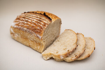 Freshly baked homemade sourdough bread loaf sliced on beige background 