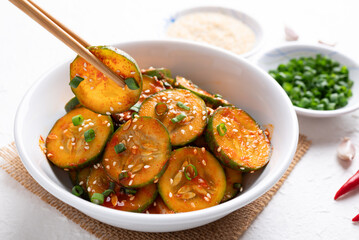 Korean cucumber salad (Oi muchim) in bowl with chopsticks on white background, Korean side dish