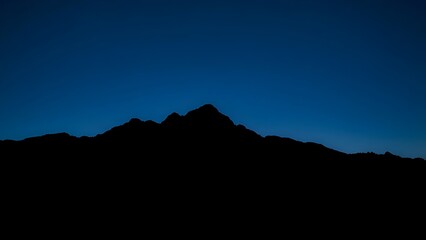 A majestic mountain silhouette against a twilight sky, radiating calm and natural beauty.