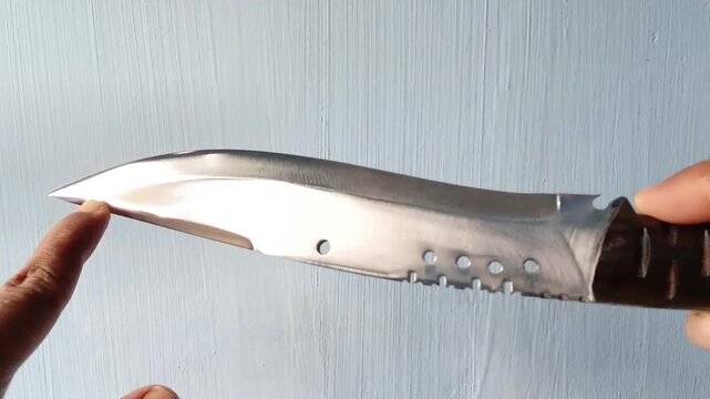 Kukri survival knife held in hand, adventure blade display close up for outdoor, camping, hunting, and survival concept stock footage. High detail shot of traditional curved knife