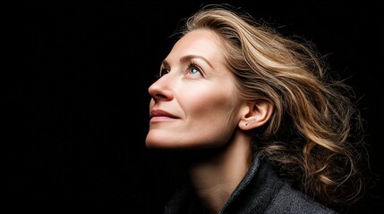 Fototapeta premium Contemplative Woman Gazing Upwards in Dramatic Lighting
