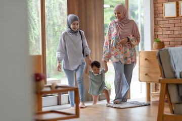 Obraz premium Asian Indonesian Muslim women walking indoors with a child