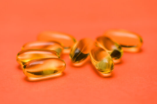 Closeup of omega fish oil clear yellow on red coral background