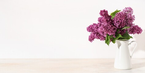 Vase with bouquet of lilac flowers on white  background with space for text