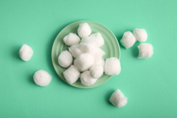 Plate with cotton balls on turquoise background