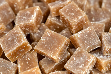 Close-up on a pile of homemade caramel candies covered with powdered sugar.
