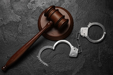Handcuffs with judge's gavel on dark background