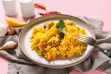Plate with tasty pilaf and ingredients on pink background, closeup