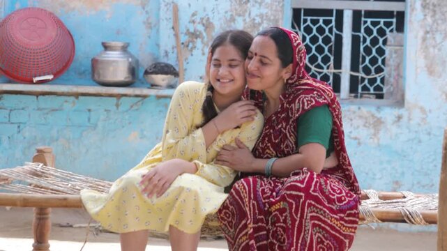 Happy rural Indian mother and child daughter kissing on her forehead and enjoy spending time together at home, Care and bonding. People of india. village life. Motherhood. 4k