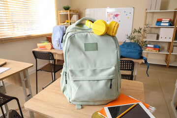 Green backpack with headphones on desk in classroom