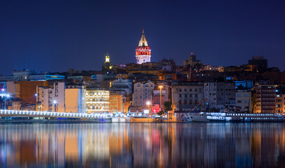 Galata Tower, Galata Bridge, Karakoy district and Golden Horn with motion speed light of passing ferry in the foreground at night istanbul - Turkey  