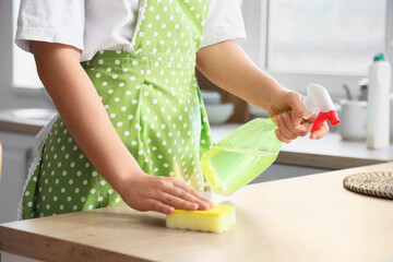 Housewife cleaning table with sponge in kitchen, closeup