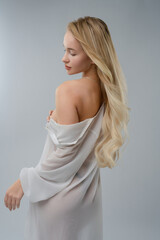 Fototapeta premium Blonde woman poses gracefully in a studio setting with soft lighting