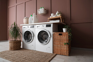 Interior of laundry room with washing machines, basket and palm plant